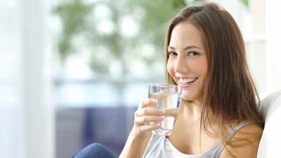 Woman smiling while drinking water.